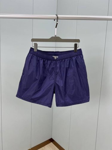 prada.普拉达 25夏季新品男士珐琅金属三角形徽标尼龙泳裤短裤，这款短裤腰头处饰以标志性的涂珐琅三角形金属徽标，再生尼龙短裤配有弹力束绳腰头、轻松穿搭便能诠