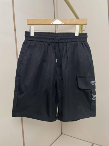 普拉达经典男士Renylon再生尼龙口袋短裤。这款短裤采用Re-Nylon再生尼龙面料打造，饰以配饰带的大号口袋。P家历史悠久的涂珐琅金属三角形徽标装饰彰显品牌