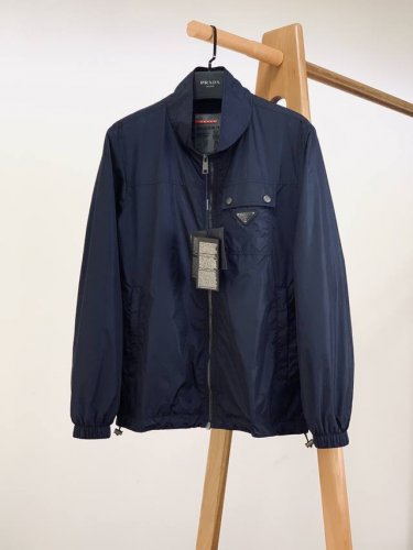 prada 普拉达 2025Ss早春新品 再生尼龙夹克，这款夹克采用再生尼龙面料制作，罗纹衣领，直筒袖拉链开合翻盖纽扣口袋，针织袖口，袖子搭配有正面涂珐琅三角形