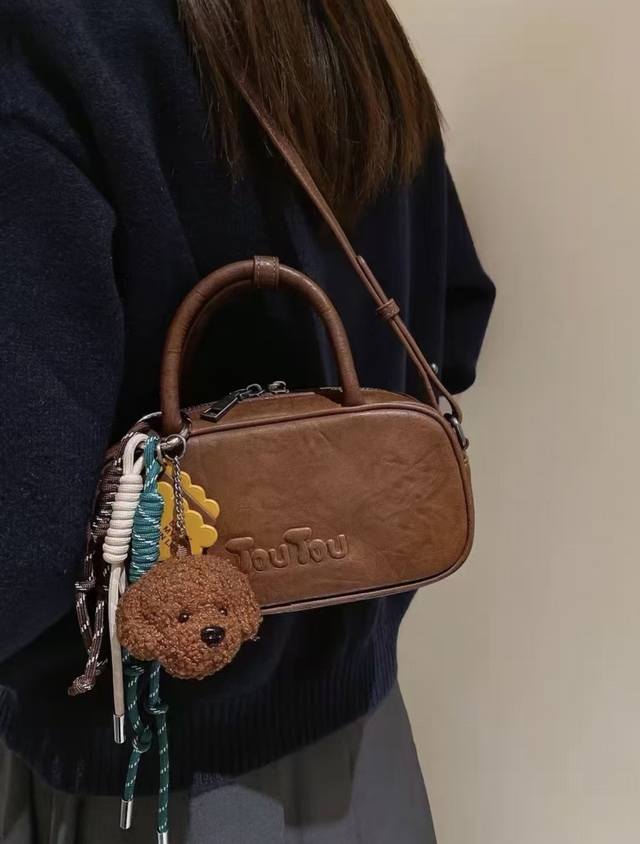 上新 配玩偶挂件 Toutou新款波士顿保龄球手拎包 小众低奢风格，高级感十足 它的设计灵感源自韩系流行文化，独特的牛仔面料搭配可爱波士顿造型，让你轻松成为街头