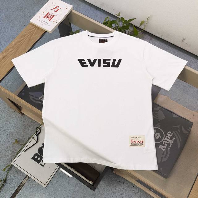 上新 款号：Ws2479 2025新款Evisu福神大M不倒翁图案Logo字母印花休闲情侣圆领短袖T恤，经典永远不会过时、人手必备款，250G双纱纯棉不起球不起