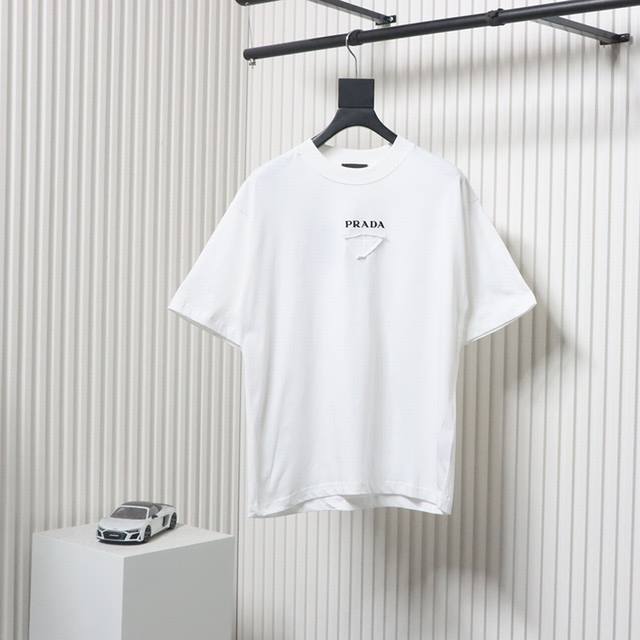 prada 25Ss 水洗植绒贴布新款T短袖 Yb定织定染面料、颜色 印花、版型 辅料 面料采用进口机器织造而成，布面纹路的独特性创造出完美的成衣效果 面料采用