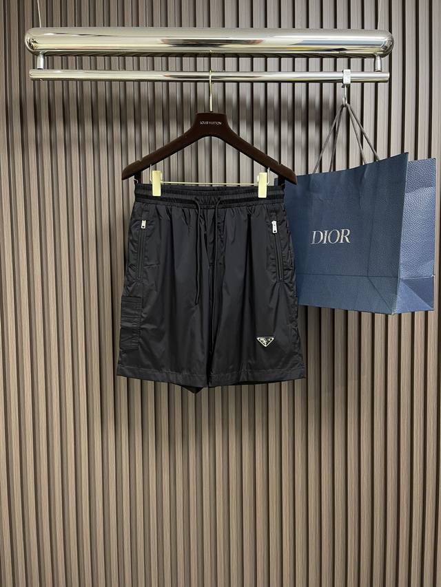 prada 2025Ss春夏新款三角标尼龙沙滩短裤，这款短裤采用优质面料，手感柔软舒适，透气性良好，适合各种场合穿着。松紧腰头设计，穿脱方便，适应不同身材，提供