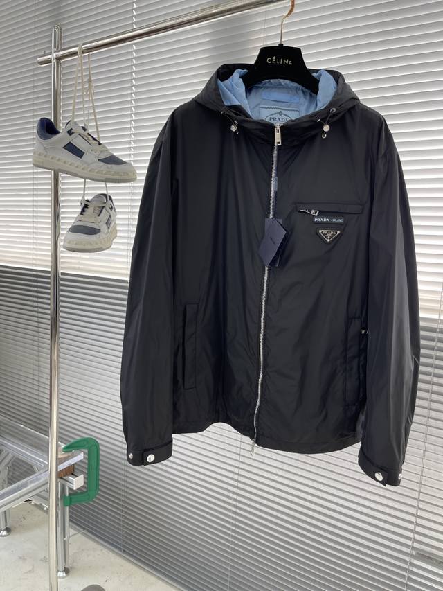 prad 25新品连帽夹克！ 先上先卖，抢占先机。 新品连帽风衣外套。这款轻质尼龙夹克和正面拉链，黑外蓝内，颇具休闲装设计特色。胸前拼接门襟。演绎品牌风范。连帽