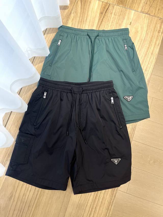 prada*普拉达 25年夏季新款短裤 标志性珐琅金属三角形徽标短裤，配有弹力束绳腰头、轻松穿搭便能诠释运动风范和现代格调 #88312# 颜色：黑色 绿色 码