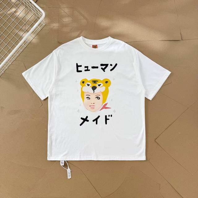 过验级Human Made插画系列老虎头套人物情侣款短袖T恤 2551 这件T恤上的图案是卡通风格。主体是一个戴着黄色老虎头套的人物脸部形象，头套上有老虎的典型