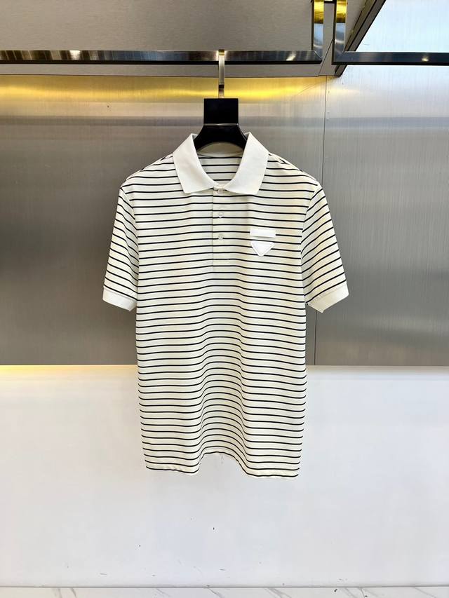 prad普拉、2025春夏新品商务休闲短袖Polo Shirt。此款短袖Polo衫饰有三角贴布绣图案和纯色饰边，面料以驻地丝光棉制成，常规版型剪裁，打造休闲廓形