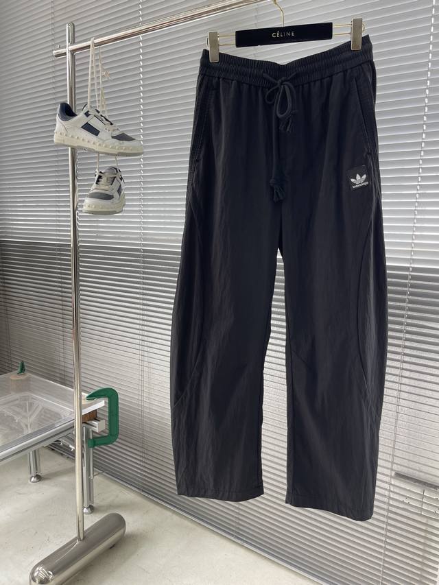 balenciag X Ad联名 三叶草梭织三条杠休闲运动裤 工艺说明：类似于风衣的梭织面料 运用超细缝盘针做高密缝盘工艺 双侧拉条平整 区别普通的做法 走线平