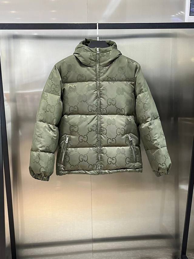 gucci Fw新款双G满Logo黑色连帽羽绒服、这款拉链羽绒服是焕新推出的配饰和成衣系列中的一款 再生尼龙由可回收利用的缝纫线和辅料制成，依托灰色背景突显品牌