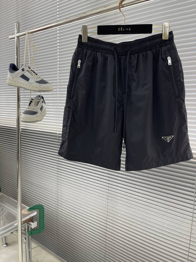 prad 25Ss春夏上新，最新Pa净色夏季短裤，精简商务风格。光滑的疏水涂层面料，轻薄便携，抽拉调节腰头镶配Pa经典三角徽标，兼具实用功能与时尚风格，尽显意式