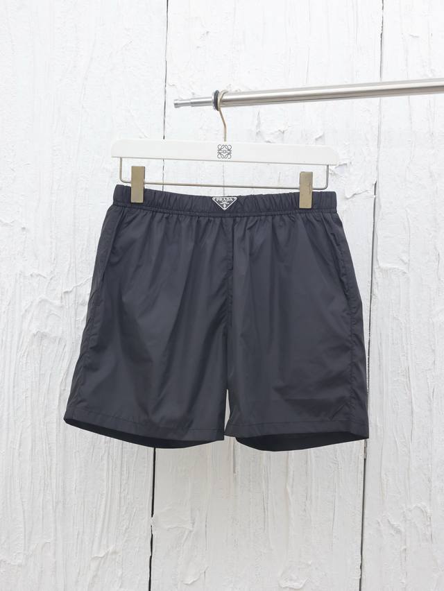 prada* 普拉达25春夏新款腰头三角标尼龙沙滩短裤 这款短裤采用优质面料，手感柔软舒适，透气性良好，适合各种场合穿着。 松紧腰设计:松紧腰头设计，穿脱方便，