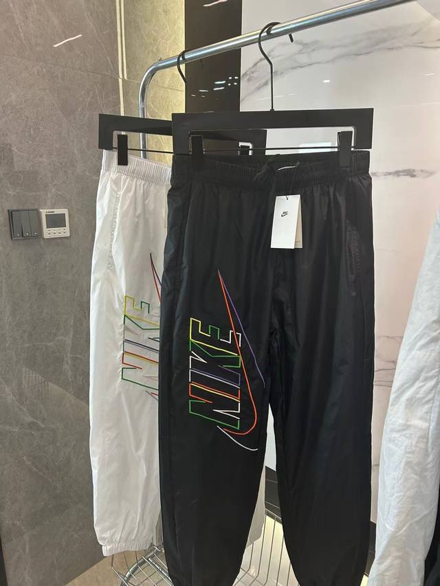 Nike 2025耐克运动款梭织大勾刺绣运动长裤 宝子们，新到的耐克梭织运动长裤别错过！黑白两经典色，搭配超炫彩色大标，出街、运动都吸睛。梭织面料，防风又透气，