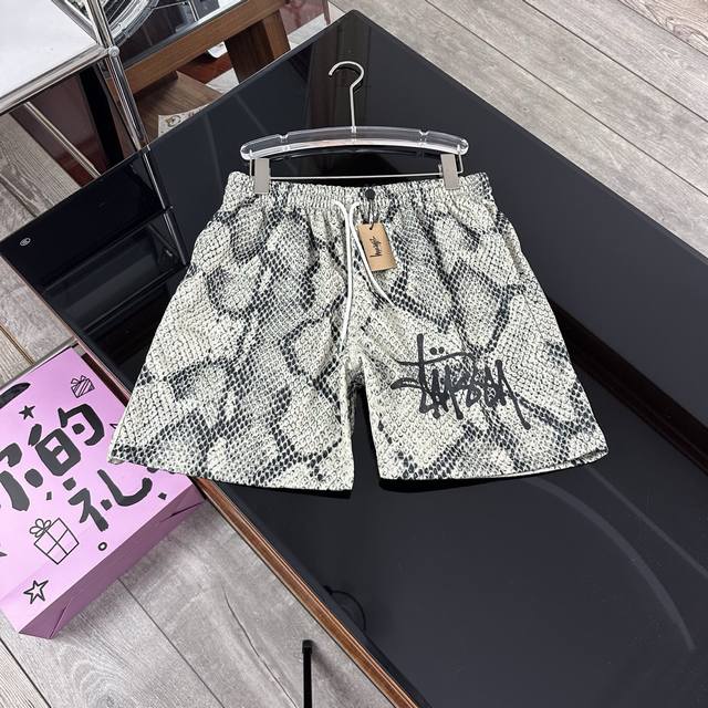 Stussy 斯图图西蛇纹短裤美式潮牌宽松版型松紧腰抽绳短裤五分裤 它作为美式潮牌单品，采用宽松版型，搭配松紧腰抽绳设计，穿着舒适又随性。五分裤长，经典Logo