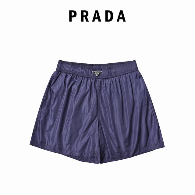 Prada 普拉达 它采用了高品质的尼龙材质，手感顺滑，上身轻盈又透气，特别适合天气热的时候穿。经典的黑色简约大气，裤腰处标志性的三角 Logo 低调又奢华，一