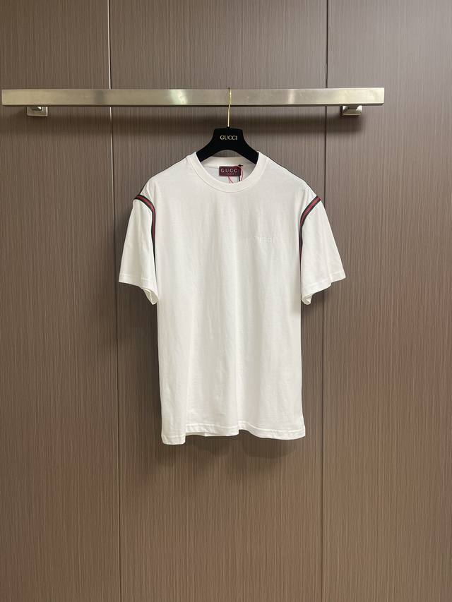 Gucci 织带刺绣短袖T恤，定制绵柔光泽平纹绸面料，标志性Gucci刺绣点缀胸前，肩部红绿织带，以落肩设计彰显时尚新高度，简约中透露优雅韵味。采用进口机刺绣工