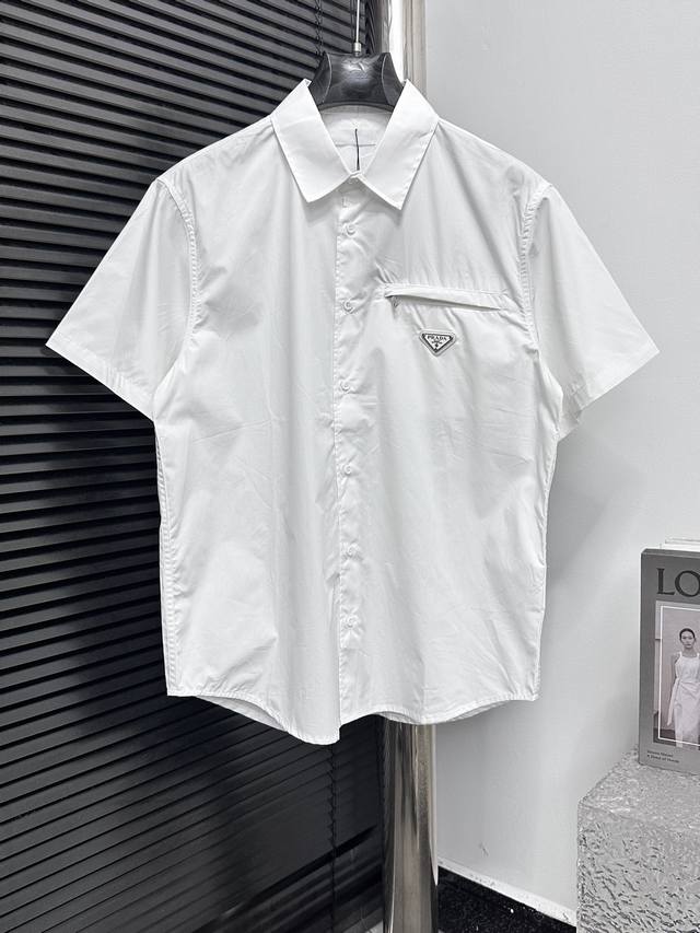Prada 普拉达24Ss三角标口袋衬衫 采用70支人丝府绸布，表面做丝光工艺，手感比较光滑。该款采用德国最新埋夹机制做而成，领口反领立体做法，双边门禁高分位坎