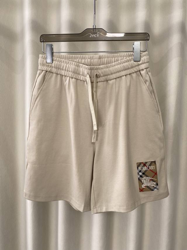 Burberry.夏季男士新品格纹标签贴花冰氧棉休闲短裤，正面左侧脚口边贴花巧妙融合Burberry格纹马术骑士徽标元素，创意重释品牌标志性设计，弹性松紧腰边带