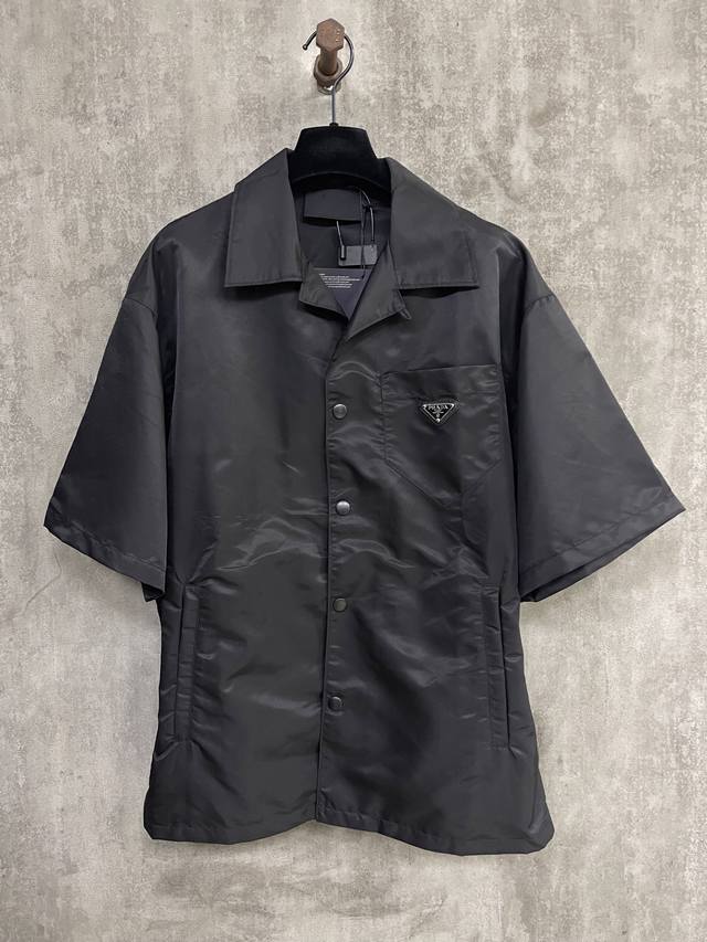 Prada 尼龙口袋翻领衬衫 面料：采用100%尼龙面料，该款面料做了过胶工艺，过胶后的成衣效果可使衣服更质感更为立体，上身更为有型。可内搭与外穿，整成衣服都采