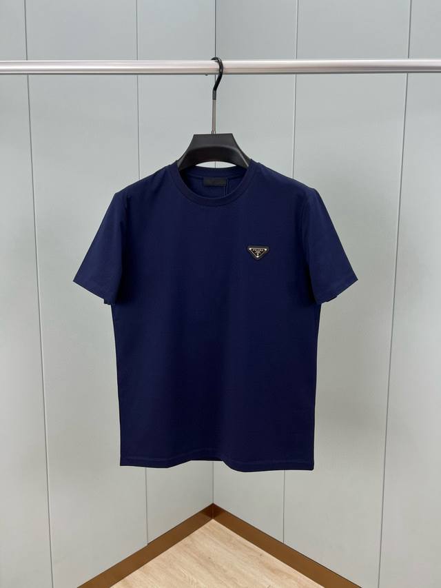 Prada.普拉达 25春夏经典涂珐琅三角形金属徽标短袖T恤，正面胸前缀饰涂珐琅三角形金属徽标为时尚设计增添经典元素，呈现衣橱必备单品。定制80支双股丝光棉面料