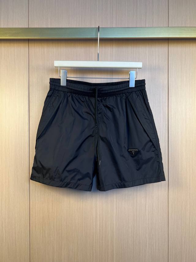 Prada 三角标尼龙短裤 定制再生幻纶尼龙织物 清爽透气 舒适贴肤 以深邃的黑为主色调 纯粹而深邃 标志性Prada三角标点缀于裤身 瞬间为整体造型注入灵魂