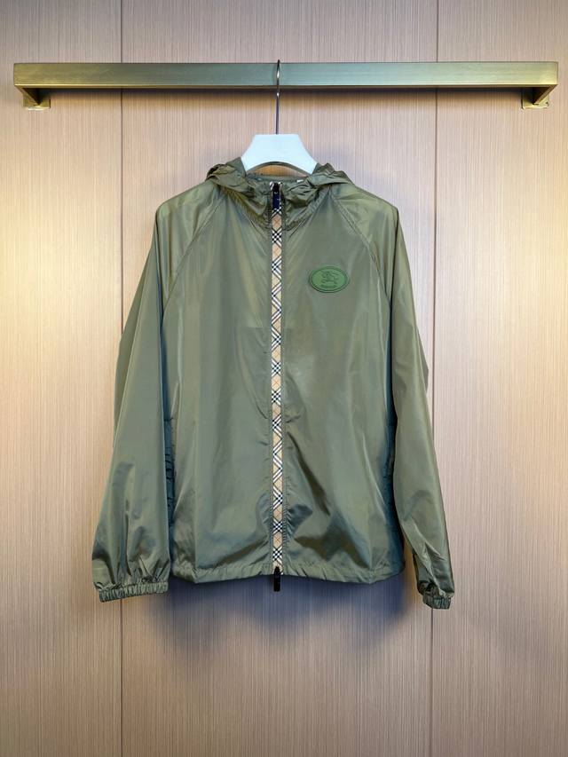 Burberry 早秋新款 尼龙连帽外套，融入 Burberry 格纹饰带和 B 字型拉链头。质地轻盈、装饰骑士印章贴花，源自 1980 年代品牌包款的典藏图案