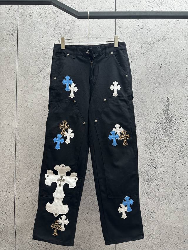 鲜明克罗心风格的黑色工装裤。克罗心是知名潮牌，以独特设计闻名。裤子上有蓝、白等颜色的十字架贴皮装饰，兼具街头潮流感与个性艺术氛围，是追求独特穿搭者的优选单品。
