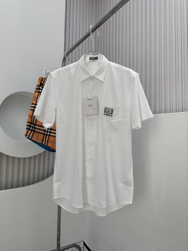 426D -Dio 24Ss春夏新款短袖衬衫饰以 Dio Charm 机织标签，突显经典的 Dio 标志。 采用白色棉和蚕丝混纺面料精心制作，胸前饰以贴袋，搭配