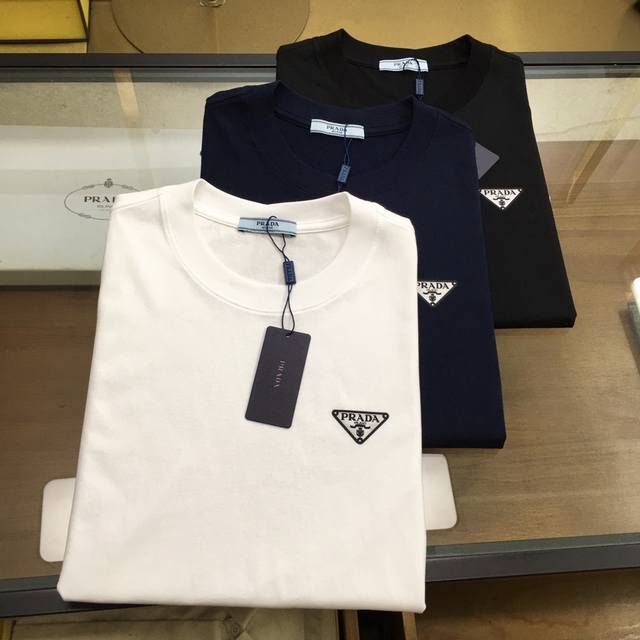 新品 Prad... 25春夏圆领短袖T恤，创新复合工艺三角标识，后幅下摆红色Logo点缀，定织高端100%长绒棉平纹针织面料，手感非常柔顺舒适，面料挺括抗皱耐