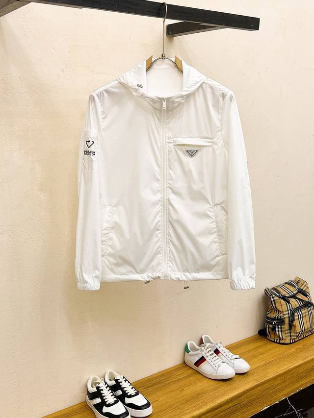 Prad普拉达 夏季最新款连帽防晒服轻薄夹克！胸前品牌Logo重工设计，既帅又轻便实用！ 高织超细腻的高科技爽滑聚酯胺纤维材质，面料的质感很高档细腻，防风防雨防