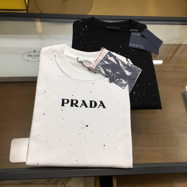 新品 Prad... 版型微阔 2025春夏首发专柜最新款短袖圆领T恤 高端订制 设计前卫时尚！品牌Logo重工艺设计 高端定制丝光云朵棉面料.手感柔软.穿着舒
