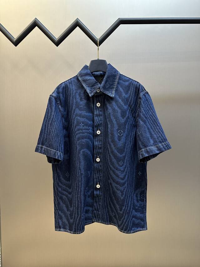 Lv 木纹 短袖牛仔衬衫 本款短袖牛仔衬衫借由当季Lv Moiré图案个性焕新，其间巧妙融入Monogram元素。同色印花映现丝绸般的莹润质感，珠光纽扣流露考究
