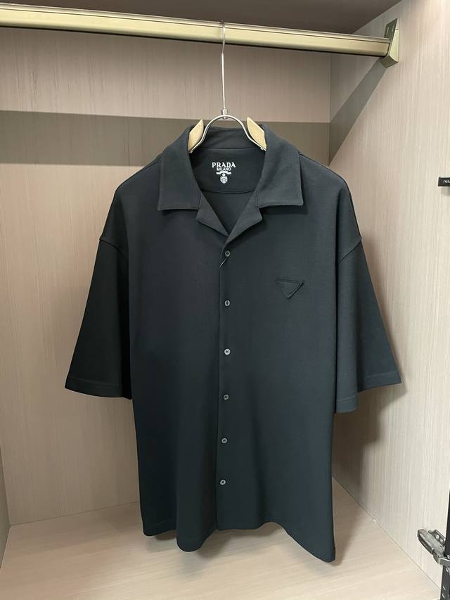 Prada 黑色短袖衬衫，简约古巴领+经典三角标，自带高级松弛感。利落剪裁适配多种风格，日常通勤、休闲出街都能穿，把低调质感稳稳拿捏~3 尺码S-Xl