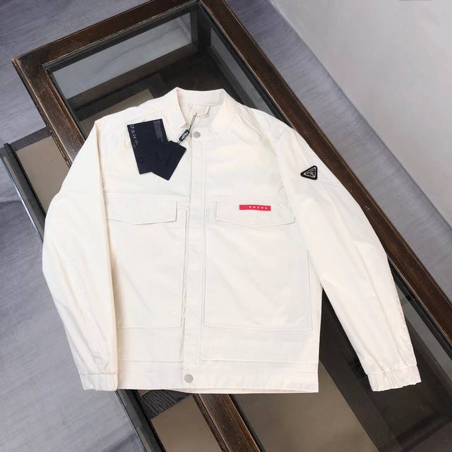 Pra*Da 普拉达 2025最新款#Pd休闲时尚棒球服工装口袋夹克款，选用了P家专业定制的轻薄科技面料制成，表面整洁光滑且富有光泽，质感透过屏幕都显而易 见，