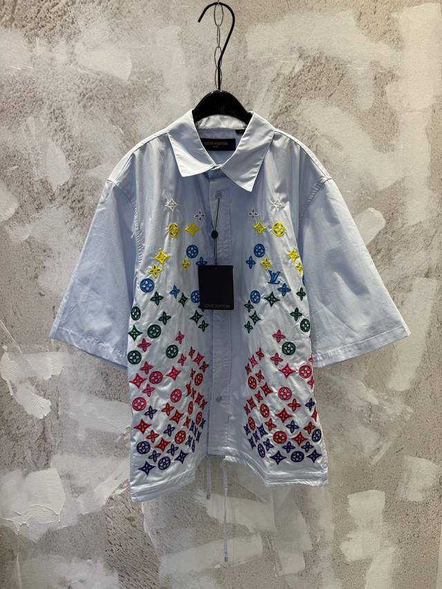 Lv 花卉老花彩色渐变镂空刺绣短袖衬衫 本款短袖衬衫取材顺滑棉质府绸，依托英式刺绣工艺为 Monogram 花卉渲染渐变色调，再将 1V 标识含蓄融入其中。腰部