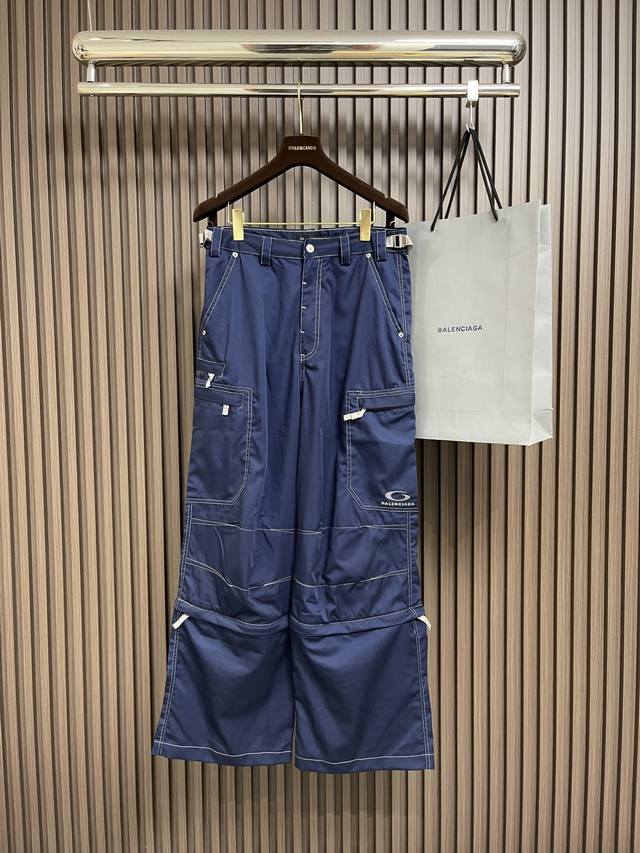Balenciaga 刺绣多功能工装裤，定制海韵儒蓝棉混斜纹绸料，多个立体口袋错落有致，左侧口袋饰Icon刺绣，增添品牌辨识度。裤腿下部可拆卸的设计，自由切换穿