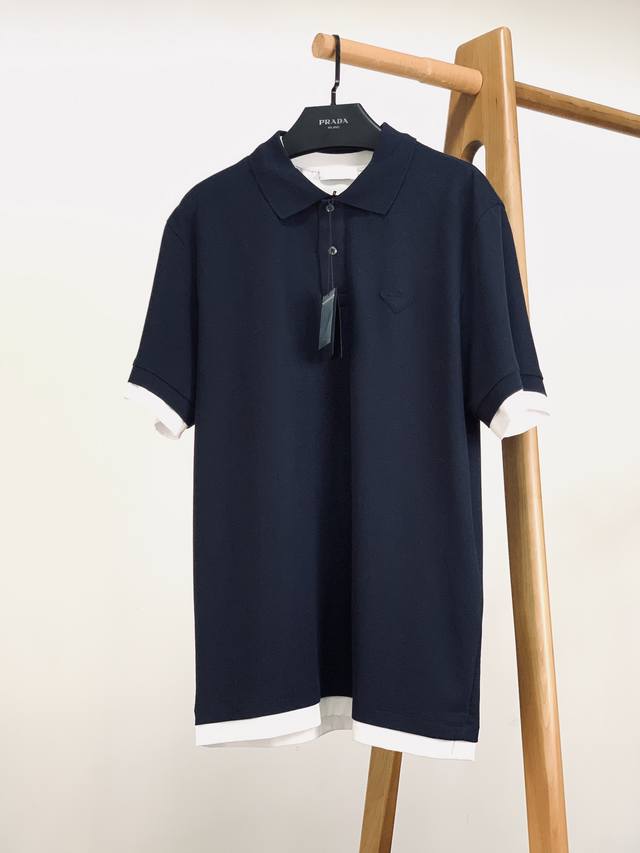 Prada 普拉达 2025Ss春夏新品 假两件Polo衫。经典藏蓝主调，暗藏假两件巧思 袖口、下摆露出纯净白边，一秒营造“叠穿层次感”，省时又时髦 领口细节：