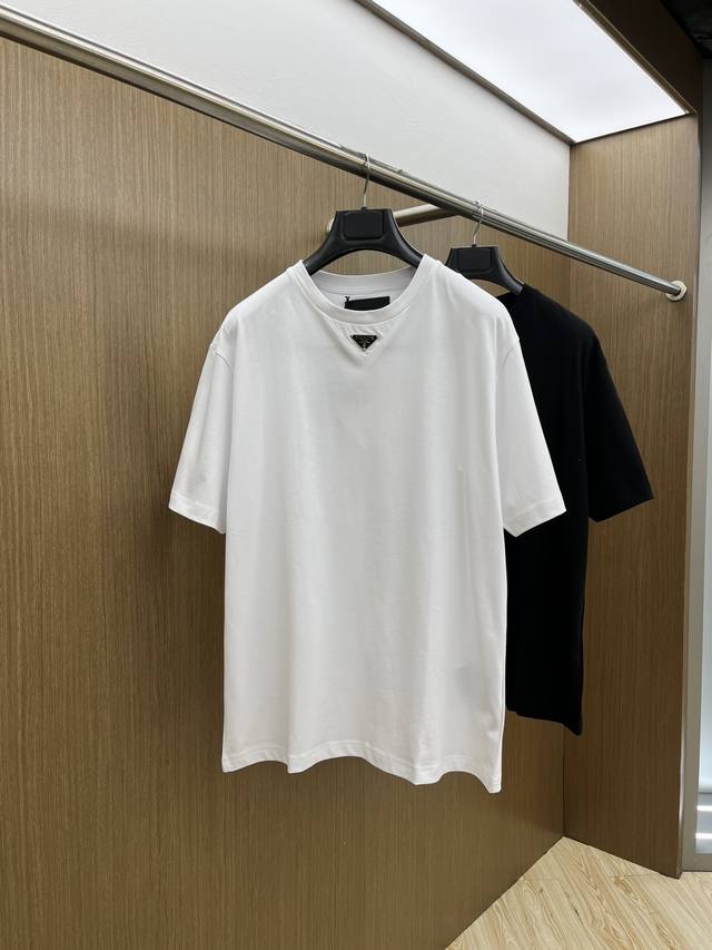 Prada 普拉达2025新款胸前三角标休闲圆领男士短袖T恤 这款棉质T恤搭载短袖和罗纹针织圆领，呈现Oversize造型。Gz标志性的涂珐琅金属三角形徽标点缀