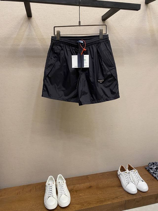 Prada 三角标尼龙短裤 定制再生幻纶尼龙织物 清爽透气 舒适贴肤 以深邃的黑为主色调 纯粹而深邃 标志性Prada三角标点缀于裤身 瞬间为整体造型注入灵魂