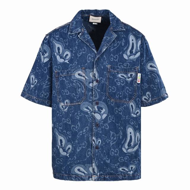 Gucci 古驰Guc 液态心形牛仔短袖衬衫灵感故事源于英国艺术家兼插画家哈蒂.斯图尔特的合作款~这个系列注入了有趣的人物角色，灵感来源于涂鸦炸弹，形状为心型、