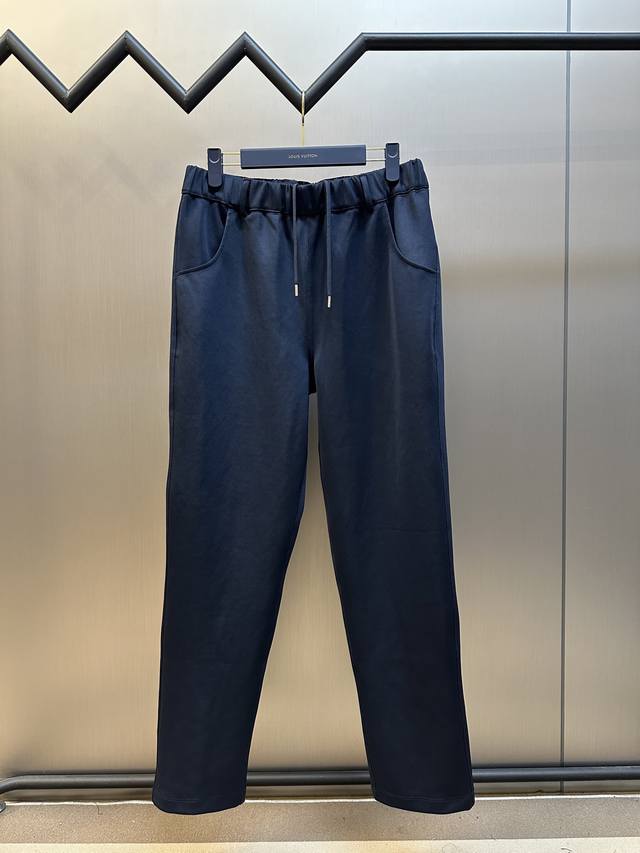 Prada 饰织物三角标长裤以80%天然棉纤维为主体，加入少量竹纤维与聚酯纤维等织造而成的健康布面料。棉纤维提供天然的透气性和舒适性，少量聚酯纤维和竹纤维的加入