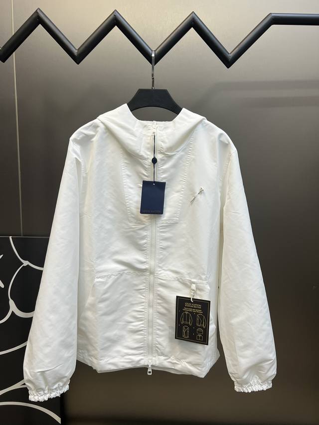 Lv双面防风夹克净色面料采用尼龙加密消光斜纹布，另一面提花面料采用50D尼龙色织提花布，净色前幅定位激光烧花，手工穿白铜材质，带Logo表面喷亮面漆三角形别针，