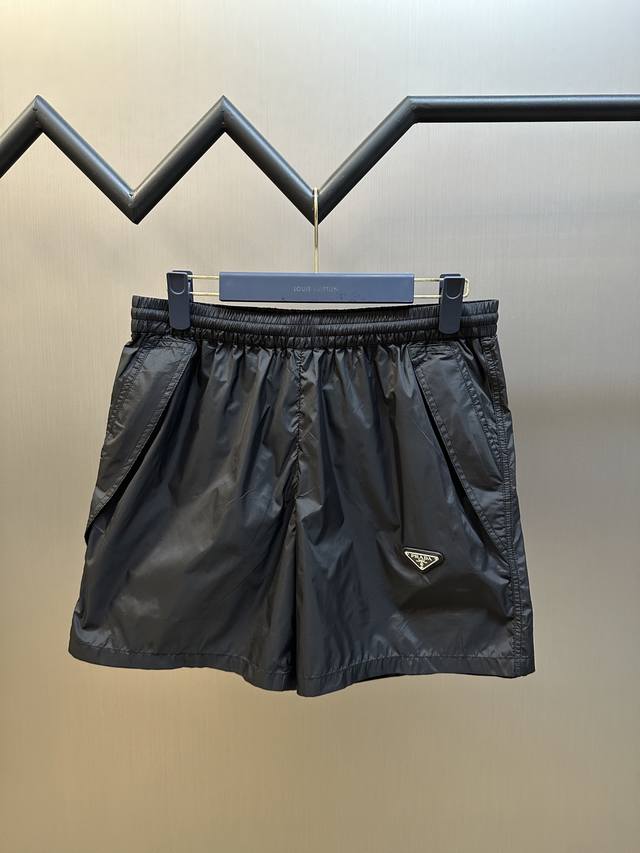 Prada 三角标尼龙短裤定制再生幻纶尼龙织物，以深邃的黑为主色调，标志性Prada三角标点缀于裤身，侧边巧妙融入的立体剪裁，增添层次与动感。Size：42 4