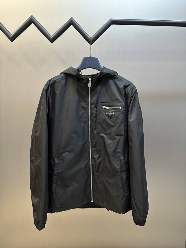 Prada 三角标拉链连帽夹克定制韵致绒锦斜纹缎料，标志性Prada三角标点缀胸前，加以口袋设计巧妙融合。人体立体裁剪，回归传统工艺手法，通过分割 折叠 抽缩
