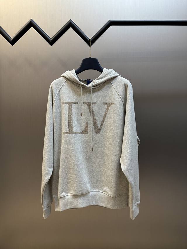 Lv 莱茵石连帽卫衣本款连帽衫为内里起绒的棉质针织搭配罗纹下摆，营造舒适休闲的穿着体验。璀璨莱茵石构筑大号 Lv 字母，耀目金属件再添潮流格调。Size：Xs