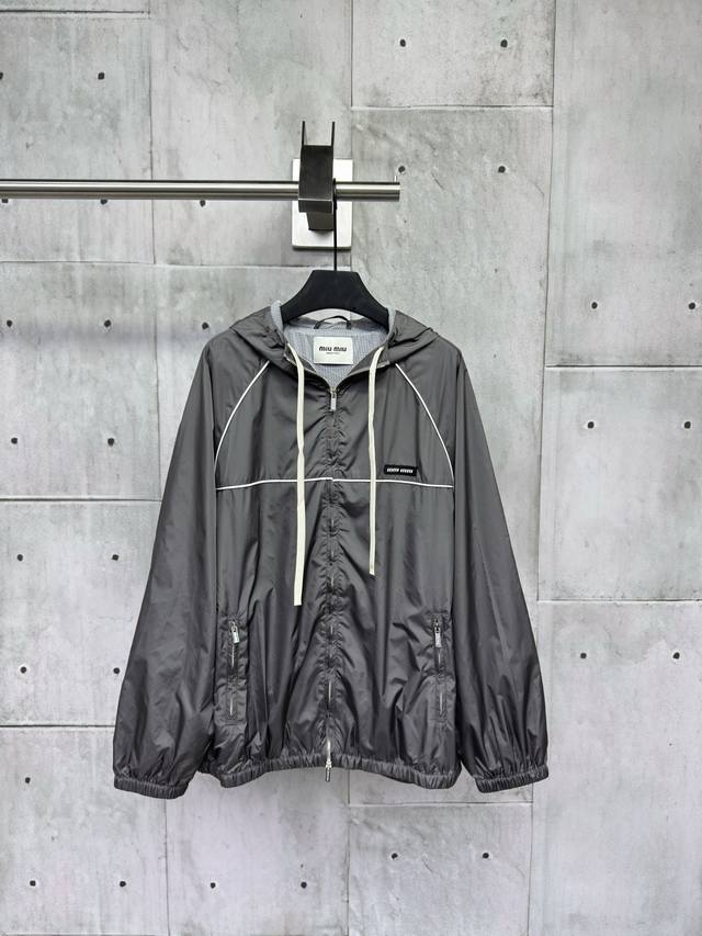 Miumiu 2025Ss小格纹冲锋衣外套定制提花面料，从外观上看，图案丰富、立体感强，定做的石灰岩色拼黑色格纹混纺面料。采用进口的提花机器，提花Logo织造章