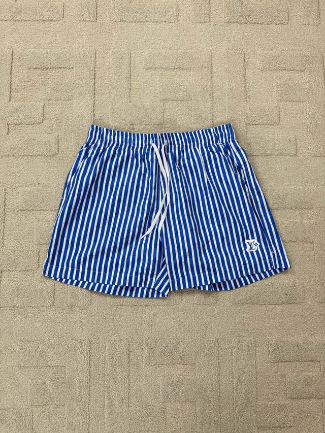 平铺细节 Lv 蓝色条纹沙滩短裤 本款沙滩短裤为全幅 Monogram 图案叠加清新条纹，尽释活力悠然的气息。橡胶 Lv Patch 贴饰栖身左腿，拉链后袋确保