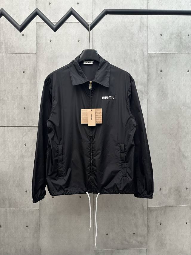Miumiu尼龙夹克 功能性织物材质： 选用尼龙材质，这种面料具有轻便、耐磨、防水防风等特点，非常适合户外活动或日常穿着。 这款夹克巧妙地将运动风格与简洁线条相