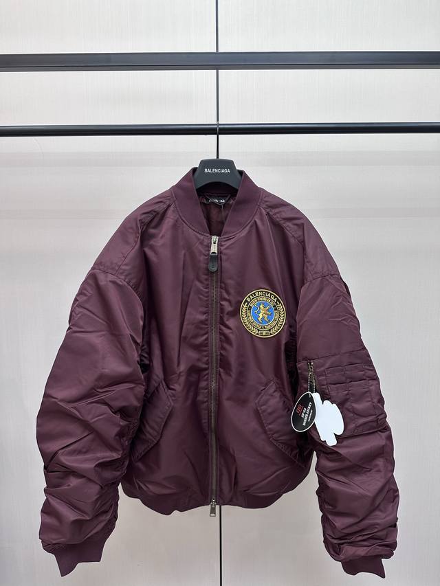 Balenciaga 狮标飞行棉服外套 前胸圆形刺绣图案章仔，订制皮革拉链头细节 正面按扣翻盖口袋，衣袖做宽松剪裁 褶皱效果 针织罗纹衣领衣袖和下摆，内里同色系