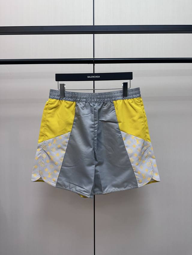 Louis Vuitton 黄灰拼接沙滩短裤 拼接质地轻盈的撞色科技面料，再借Monogramglow印花嵌饰点明品牌身份。弹力腰部和透气侧开衩确保舒爽体验，可