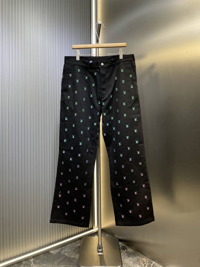 Louis Vuitton 渐变刺绣字母牛仔裤 采用水洗黑色牛仔布制成，全身刺绣有 1V Blason 图案，体现了春季系列精致的渐变主题，流行色彩从浅绿色渐变
